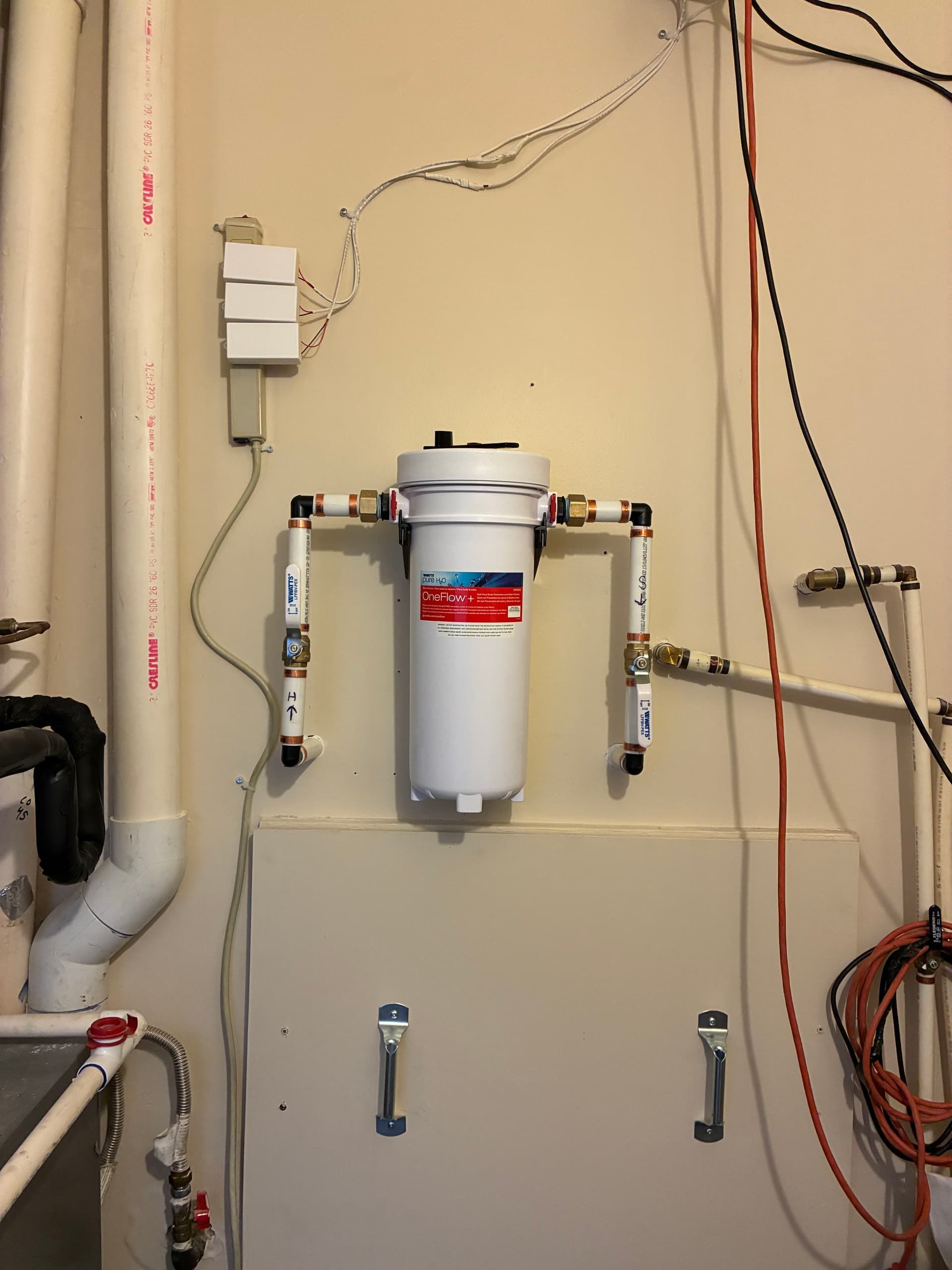 Wall-mounted water filter system with pipes and wiring in a utility room