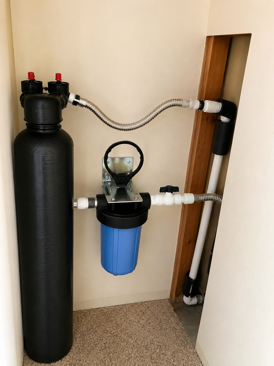 Water softener and blue filter tank installed in a utility closet with connecting pipes and hoses