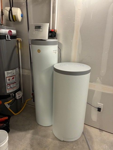 Two white cylindrical appliances beside a water heater in a utility room