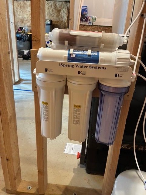 Wall-mounted under-sink reverse osmosis water filtration system with white and blue canisters and tubing