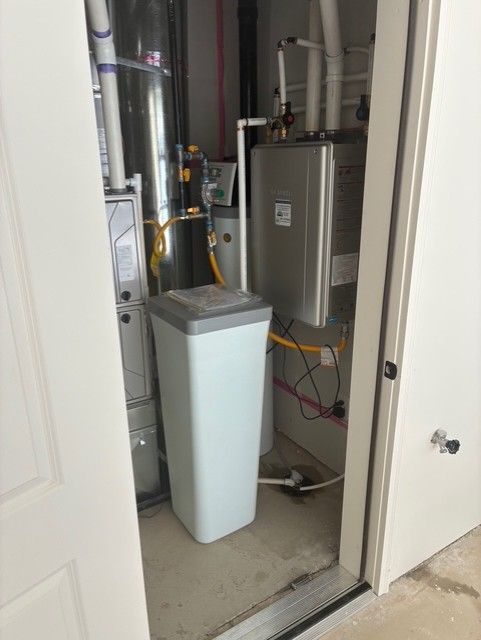 Utility closet with HVAC equipment, pipes, and a white trash bin in the doorway