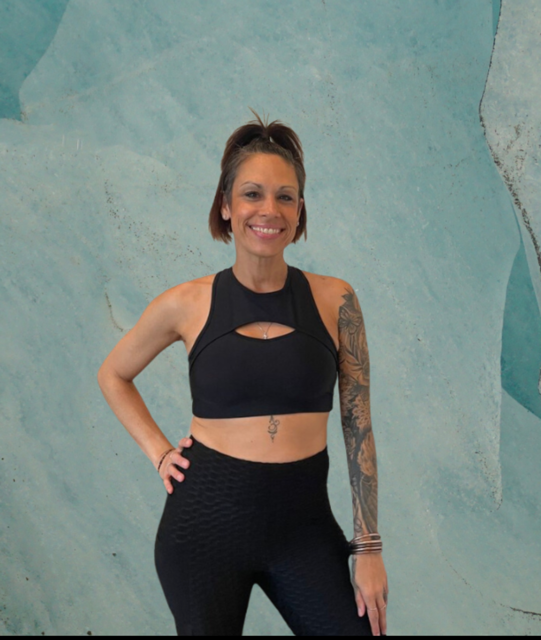 A woman is doing a yoga pose in front of a wooden wall