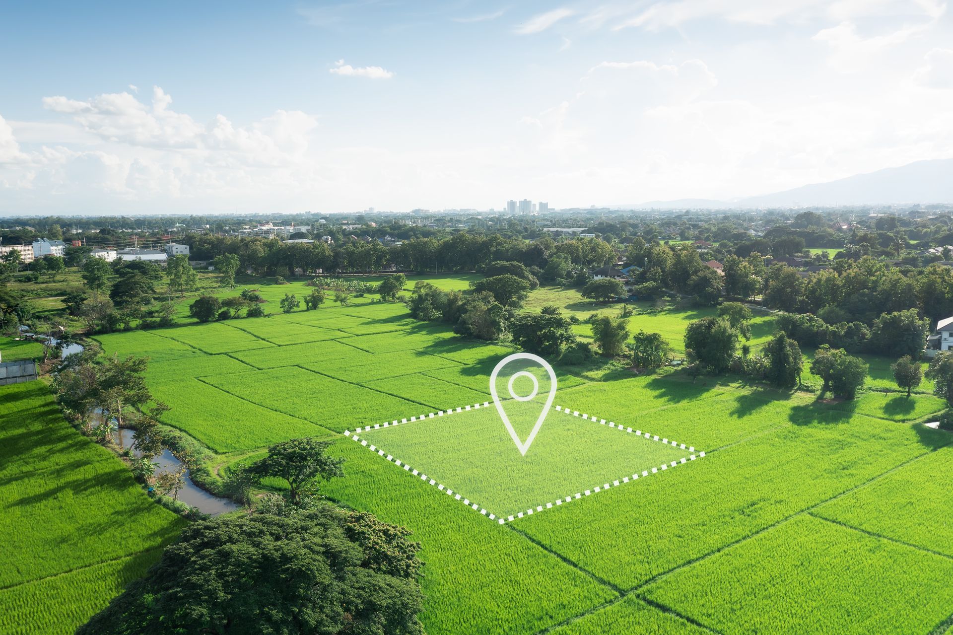 Aerial view of green field with location marker; town in background. Aerial view of green field with location marker; town in background.