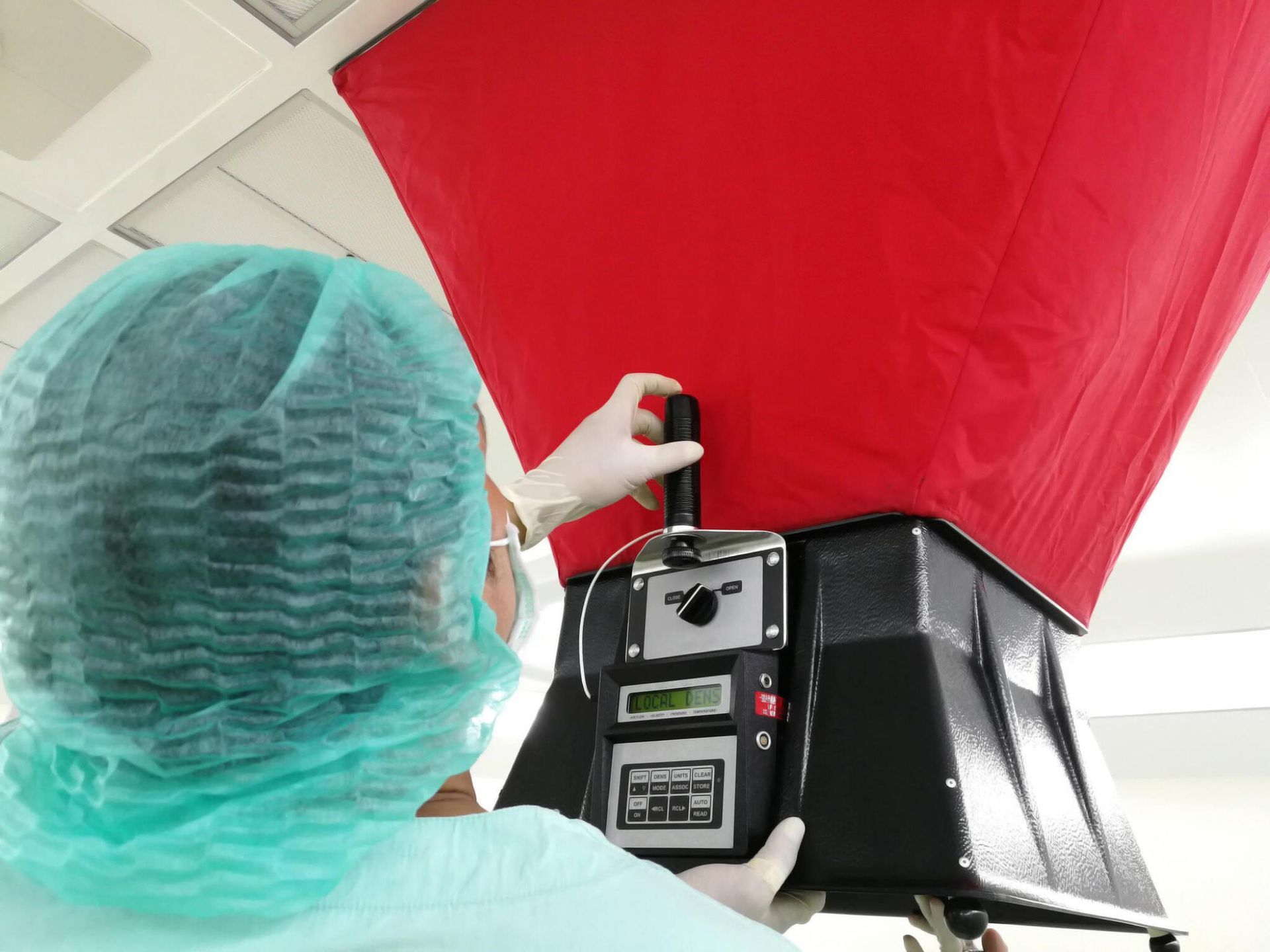 A person in a surgical gown is holding a red object