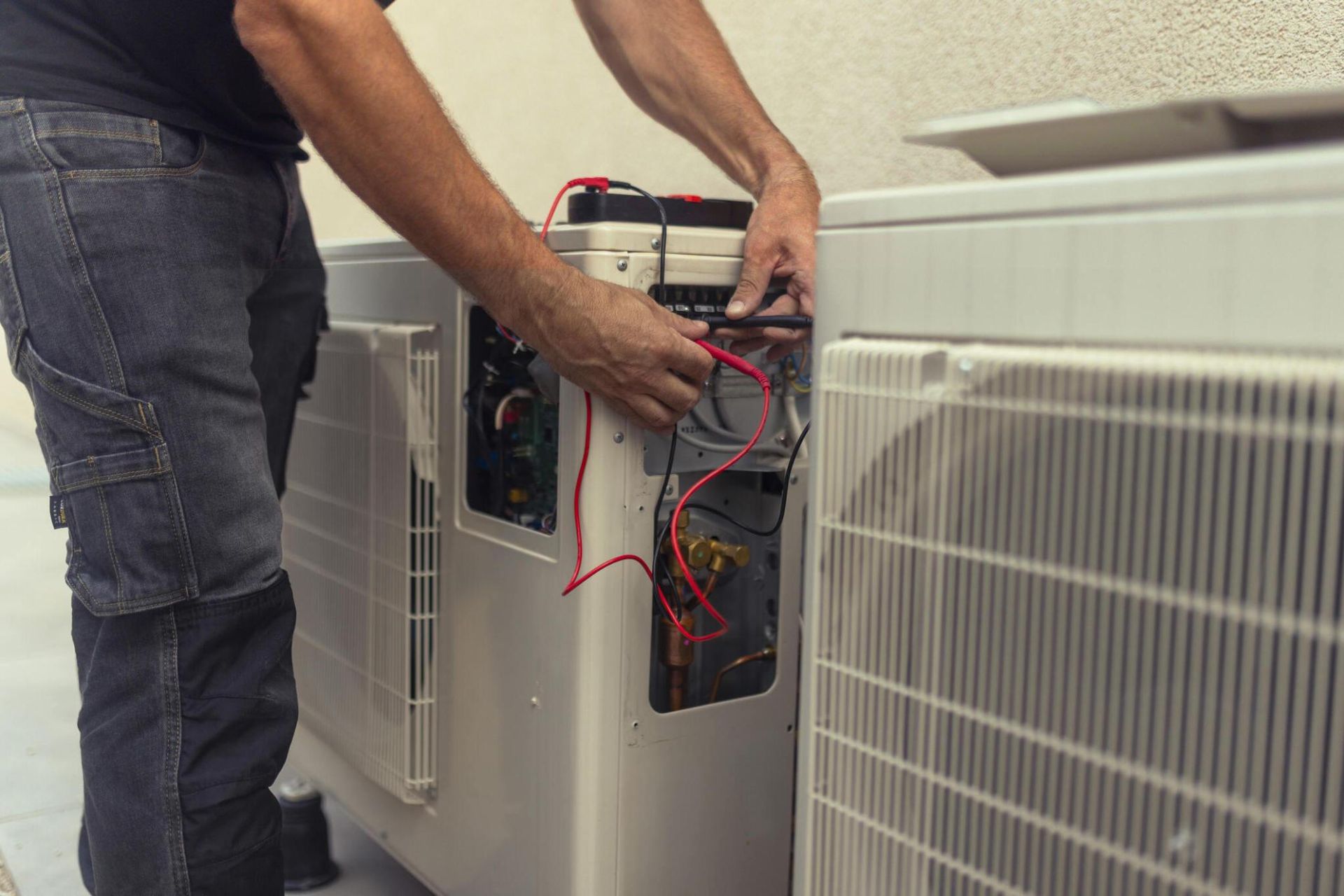 A man is working on an air conditioner outside of a building.