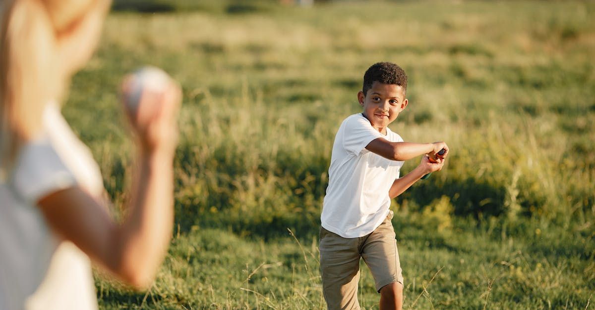 Two people outdoors in a field, one boy reaching out while another stands blurred in the foreground.