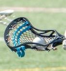 Close-up of a black and blue lacrosse stick head with netting on a grassy field
