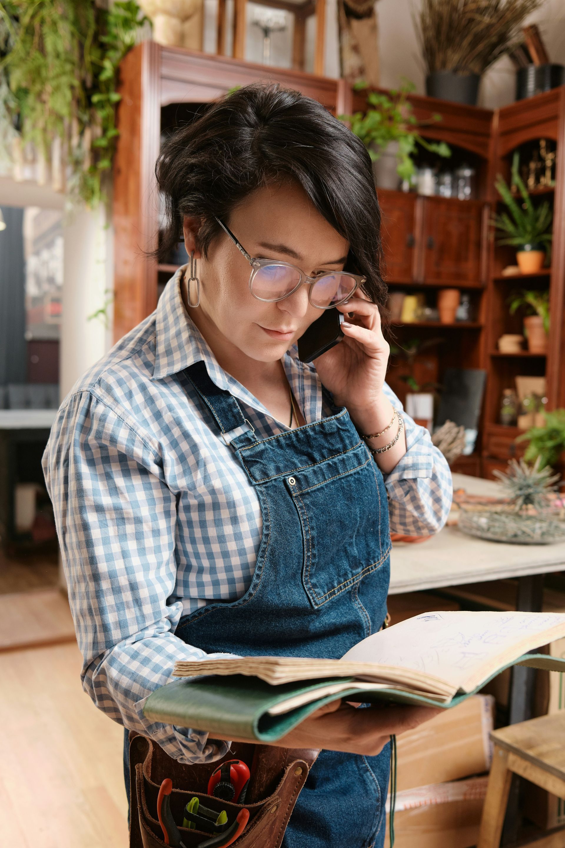 A woman is talking on a cell phone while reading a book.