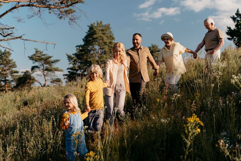 A family is walking through a field holding hands.