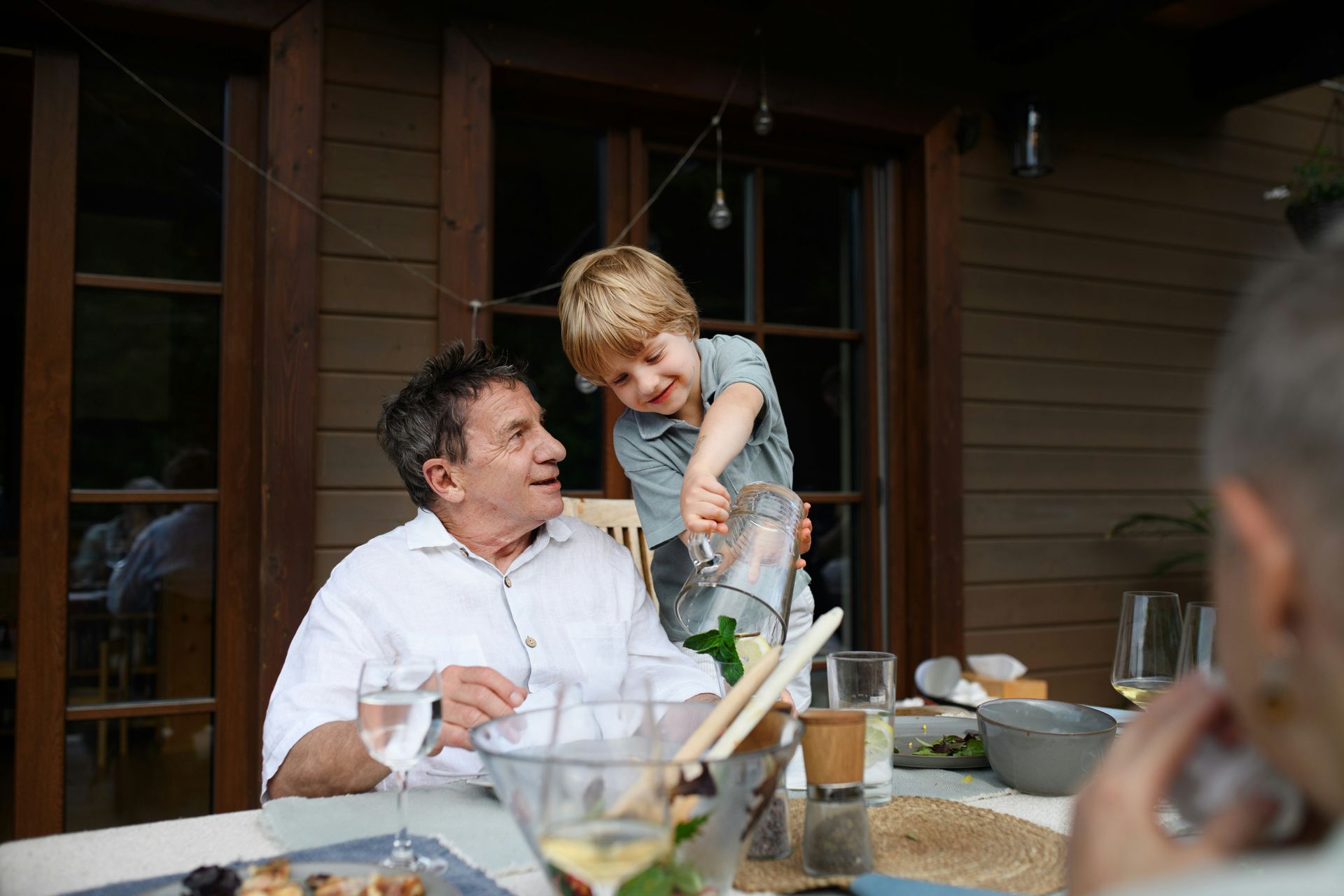A man is holding a little boy in his arms while sitting at a table.