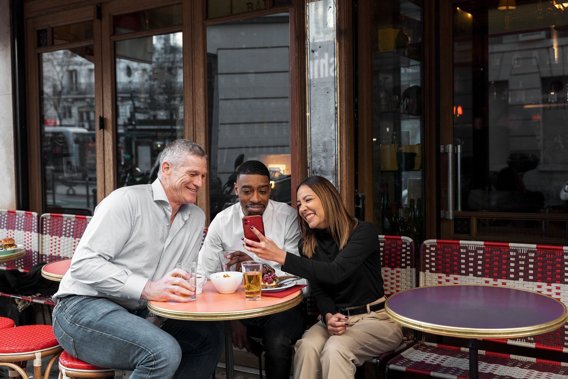 A group of people are sitting at a table outside of a restaurant.