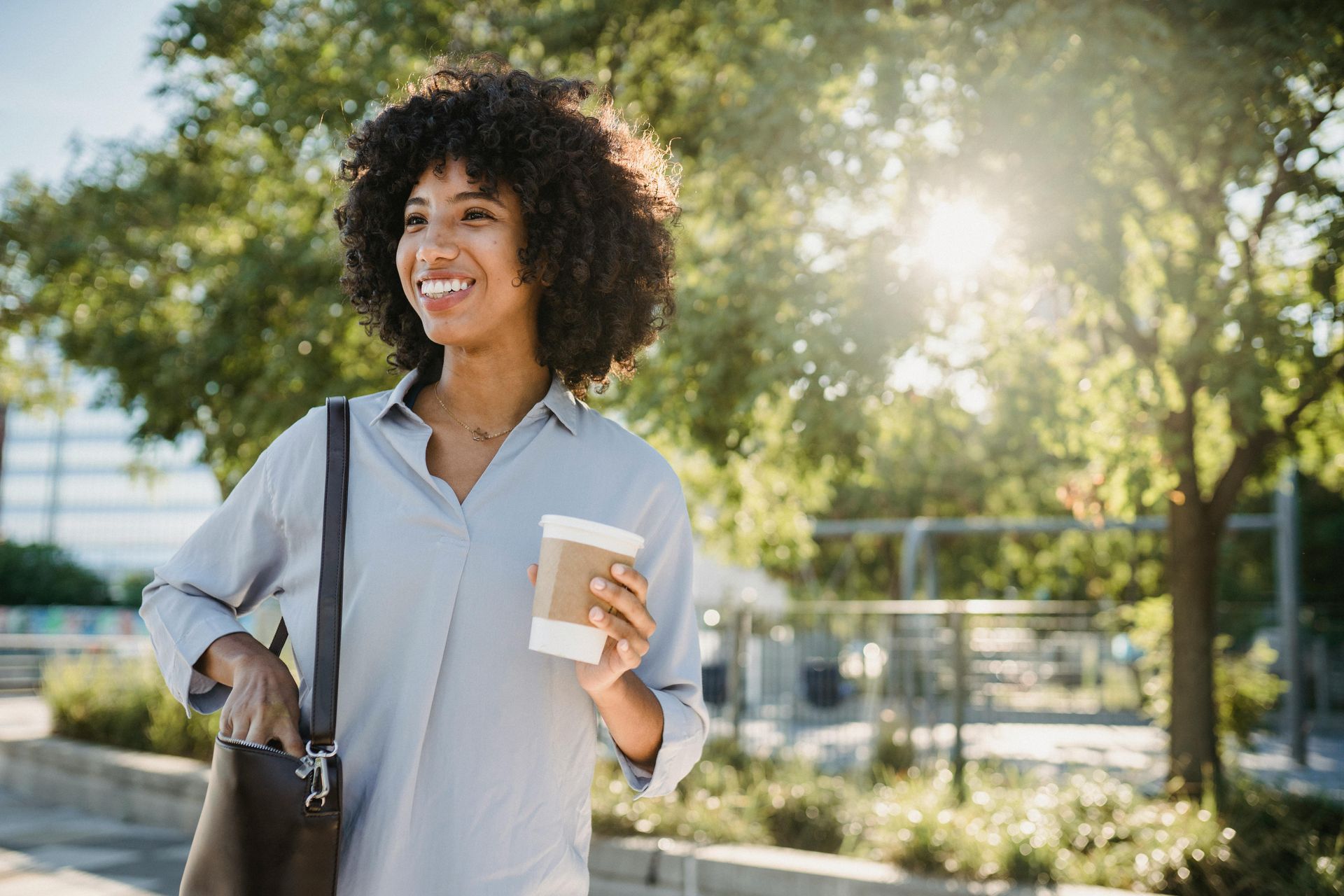 A woman is walking down the street holding a cup of coffee.