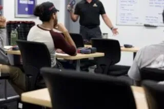 Training room with seated attendees and an instructor standing by a whiteboard