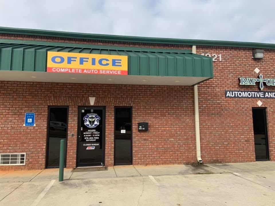 Brick auto service office with green awning and blue “OFFICE” sign over the entrance.