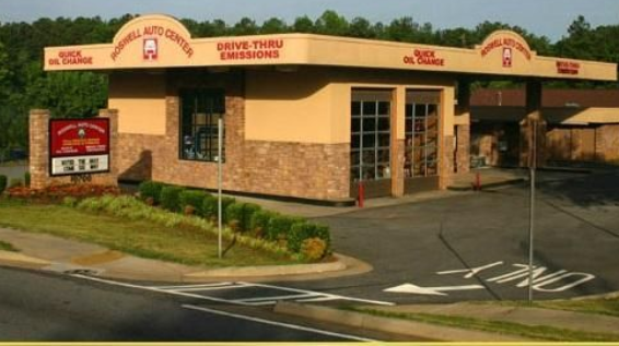 Fast-food restaurant exterior with tan stucco walls, red trim, drive-thru sign, and empty parking lot