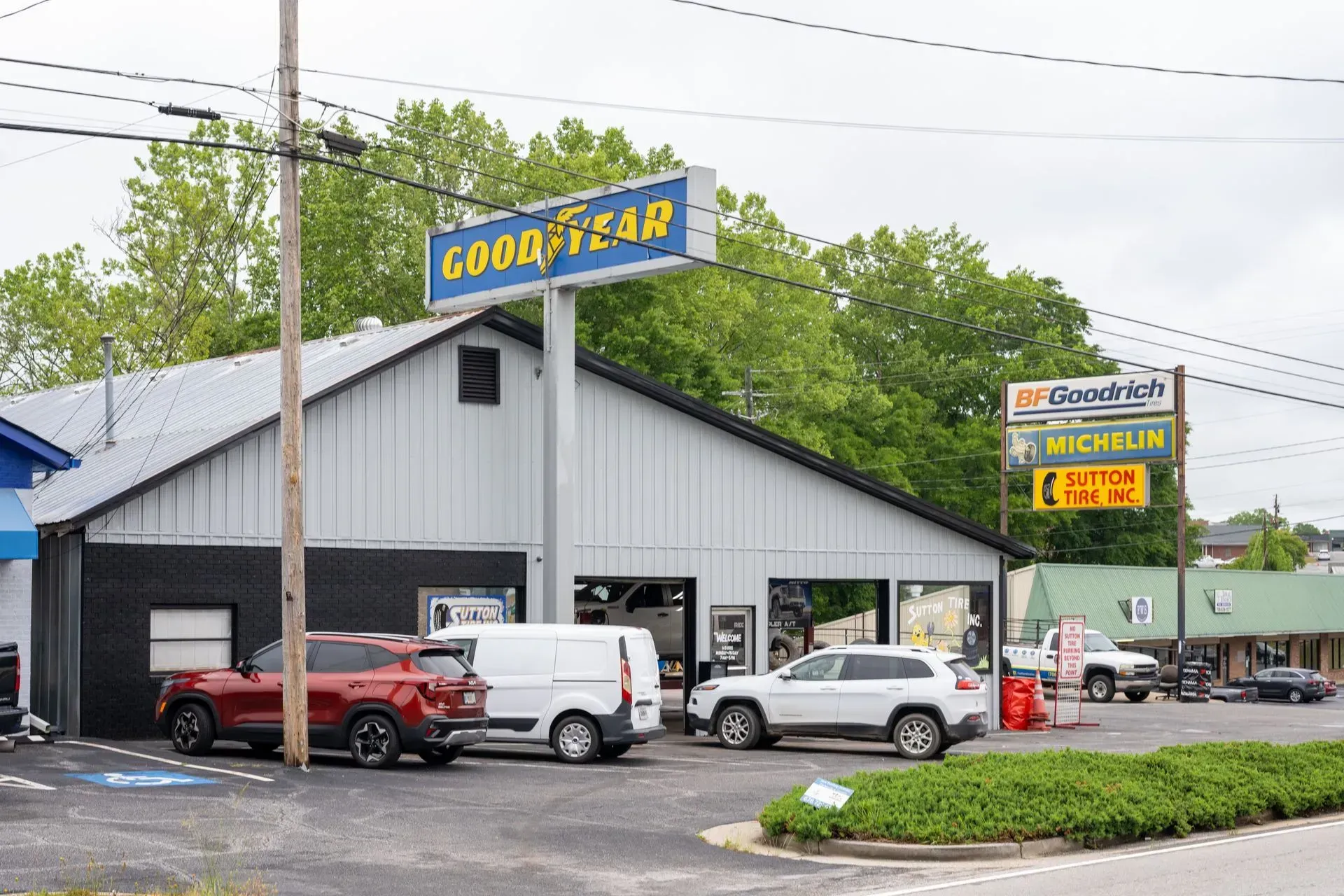 Goodyear tire shop with cars parked outside under a blue sign and overcast sky