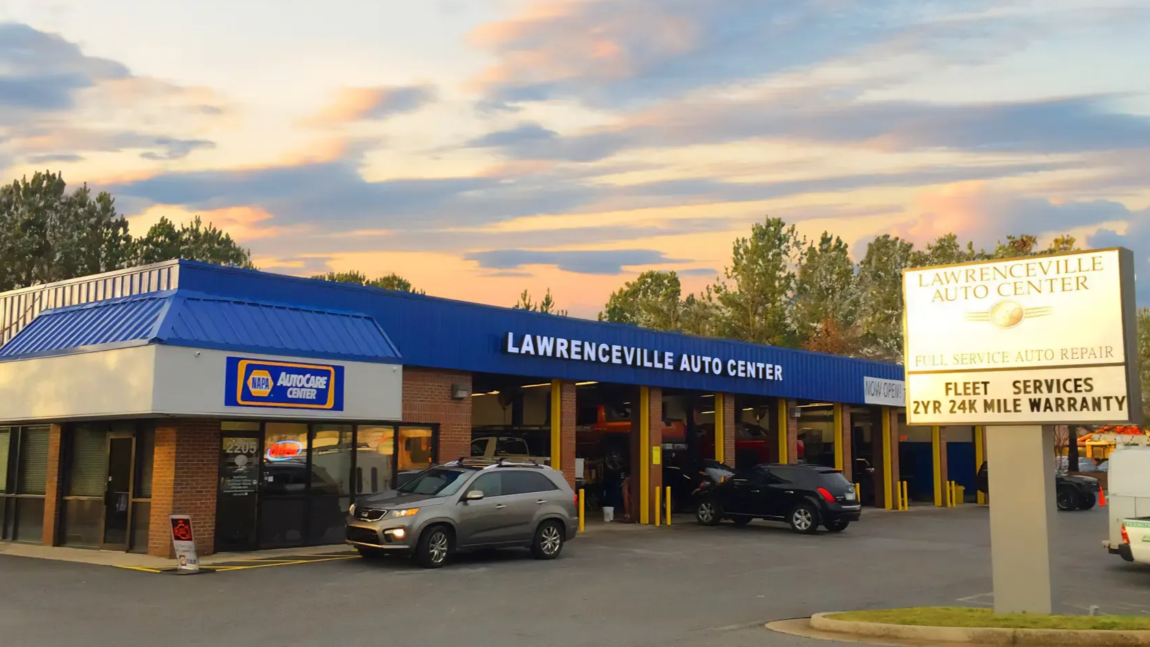 Lawrenceville Auto body shop at sunset with parked cars and a service sign in front