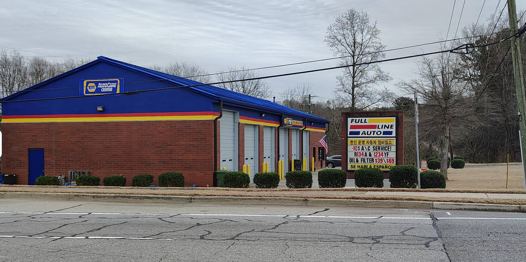 Small brick storefront with blue roof and sign, viewed from across a road on an overcast day