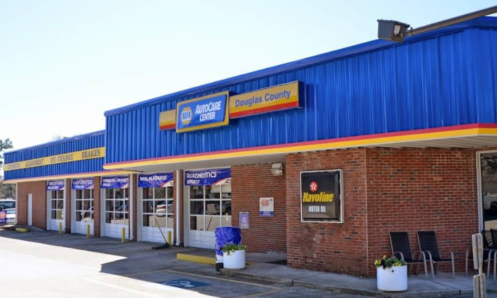 Strip mall storefront with blue awning, brick facade, and glass entrance doors on a sunny day