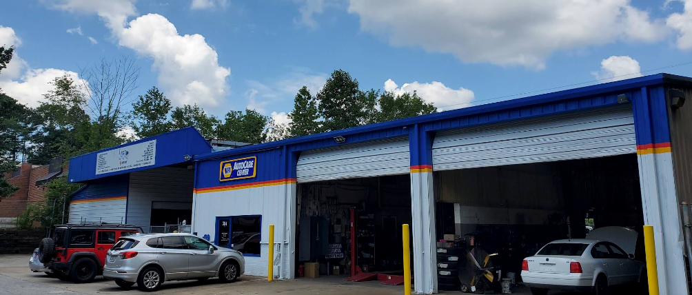 Blue auto service garage with cars parked outside under a cloudy sky