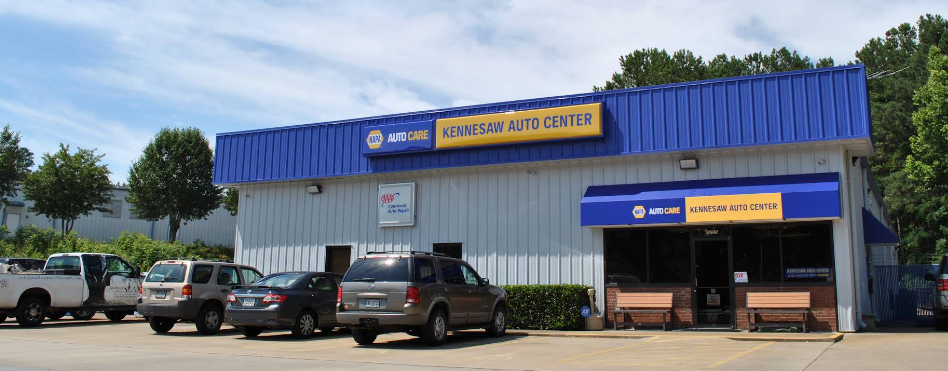 Blue auto repair shop with parked vehicles and open service bays on a sunny day