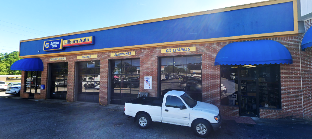 Small brick storefront with blue awnings and a white pickup truck parked outside