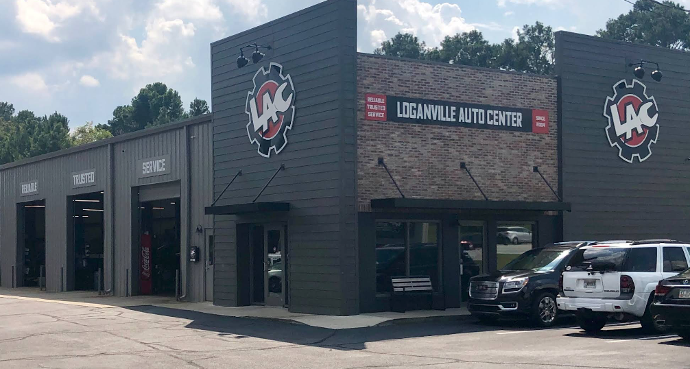 Exterior of Loganville Auto Center, a gray building with red and white signage and parked vehicles outside