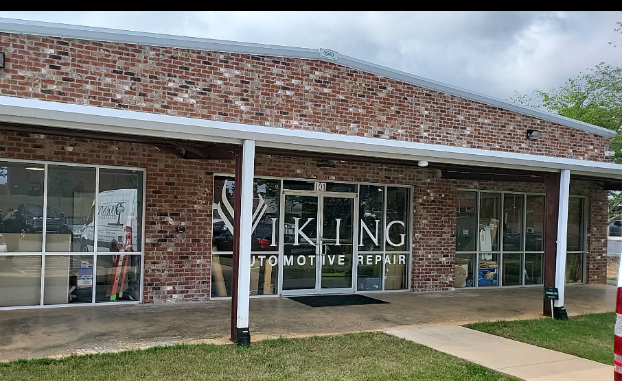 Brick storefront with large windows and a sign reading “King Automotive Repair” under a cloudy sky