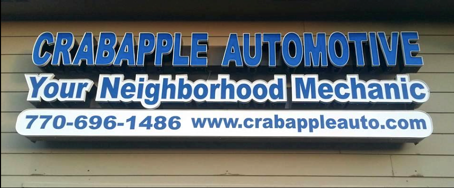 Crabapple Automotive sign with “Your Neighborhood Mechanic,” phone number, and website on a tan building side