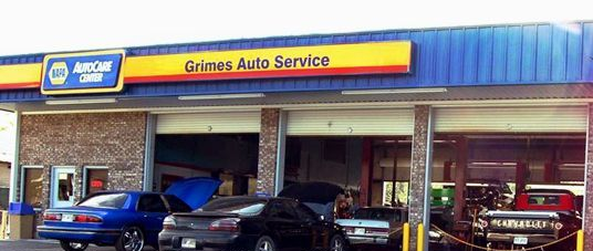 Grimes Auto Service storefront with several parked cars under a blue awning