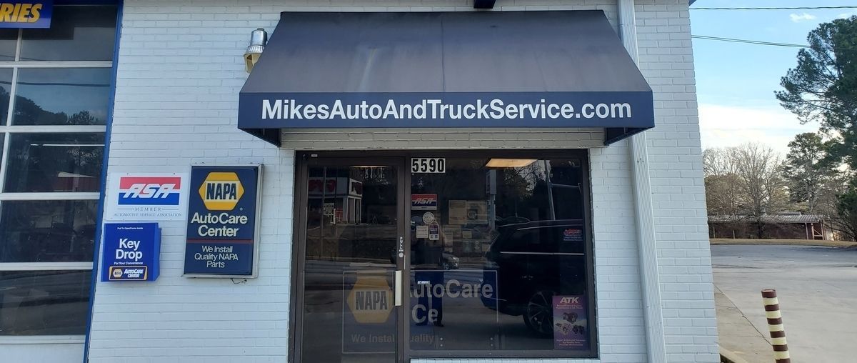 Mike’s Auto and Truck Service storefront with blue awning and glass entrance on a sunny street.
