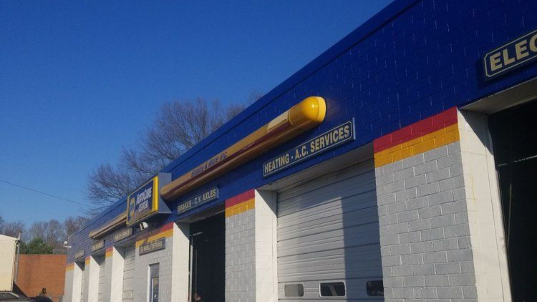 Blue industrial building with gray garage doors and yellow trim under a clear sky