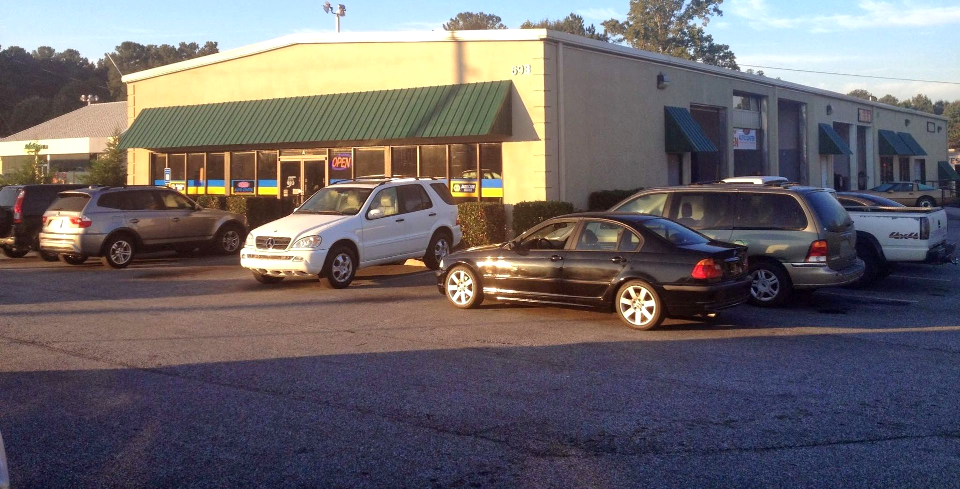 Parking lot outside a green-awning storefront with several parked cars in front
