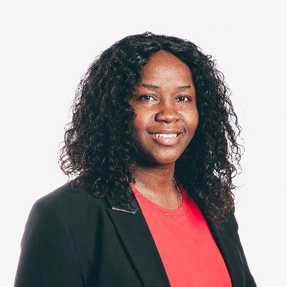 Woman in a black blazer and red top smiles against a white background.