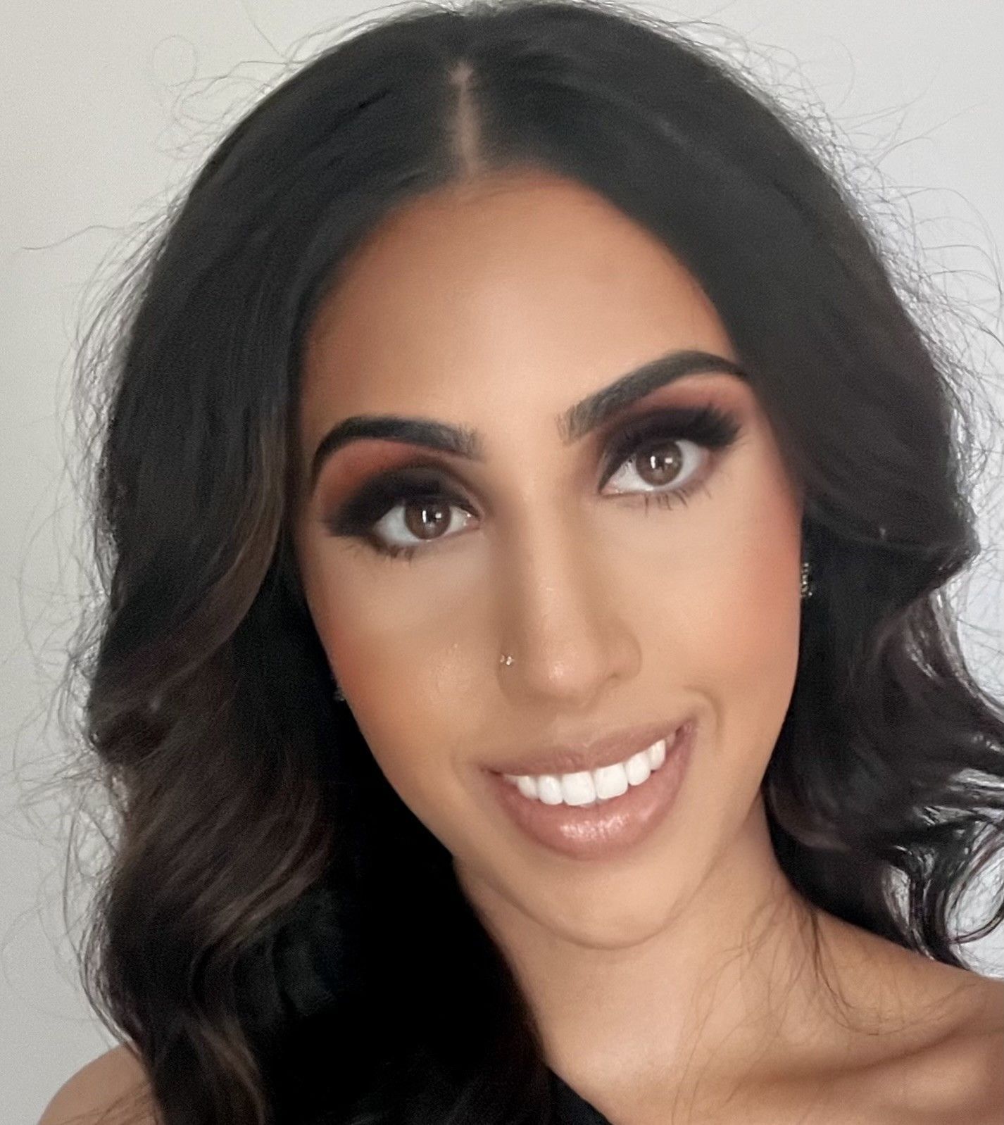 Woman with dark wavy hair and makeup smiles at the camera.