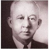 a black and white photo of a man in a suit and tie .