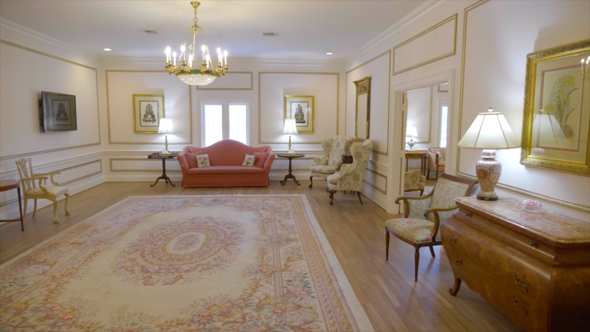 Elegant room with light wood floor, ornate furniture, and a large patterned rug.