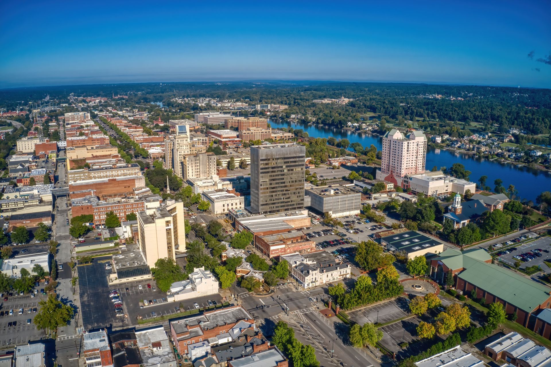 Aerial view of Sacramento, CA. City buildings and streets with the American River in the distance. Clear blue sky.