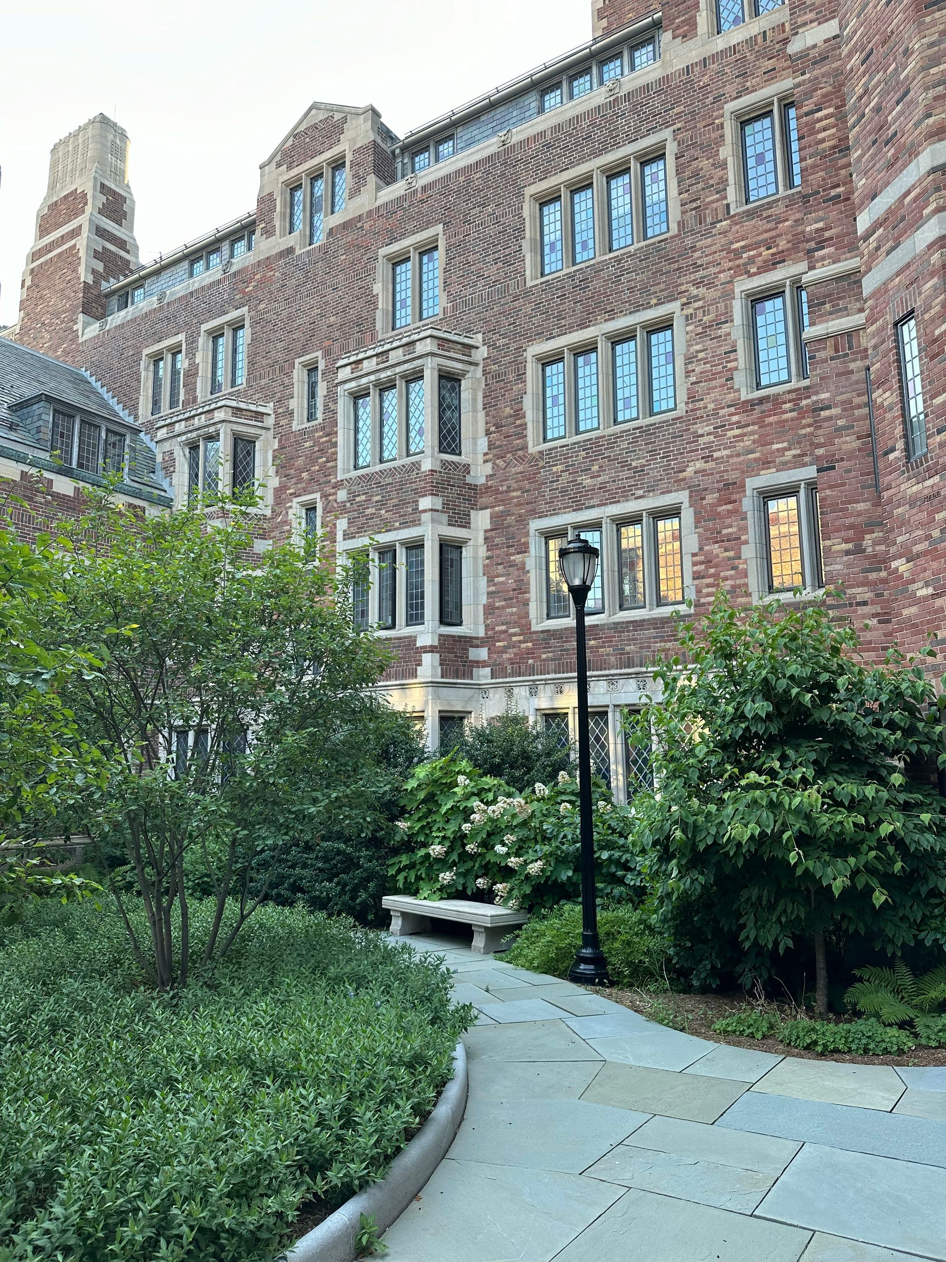 Brick building with white columns, clock tower, and green lawn under a blue sky.