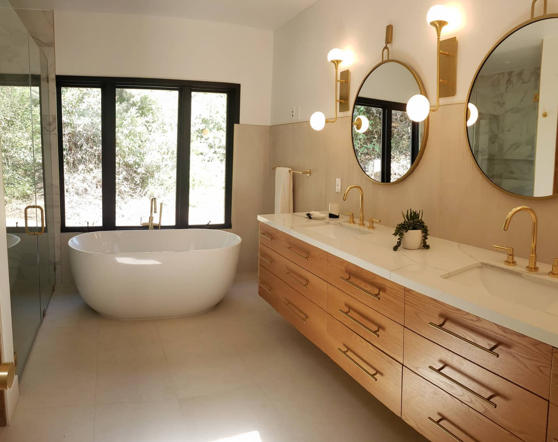 A bathroom with two sinks , a tub , and two mirrors.