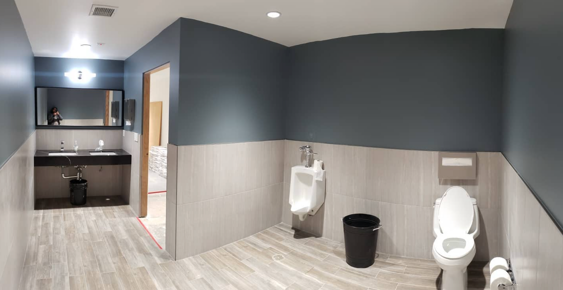 A bathroom with two urinals , a toilet , and a sink.