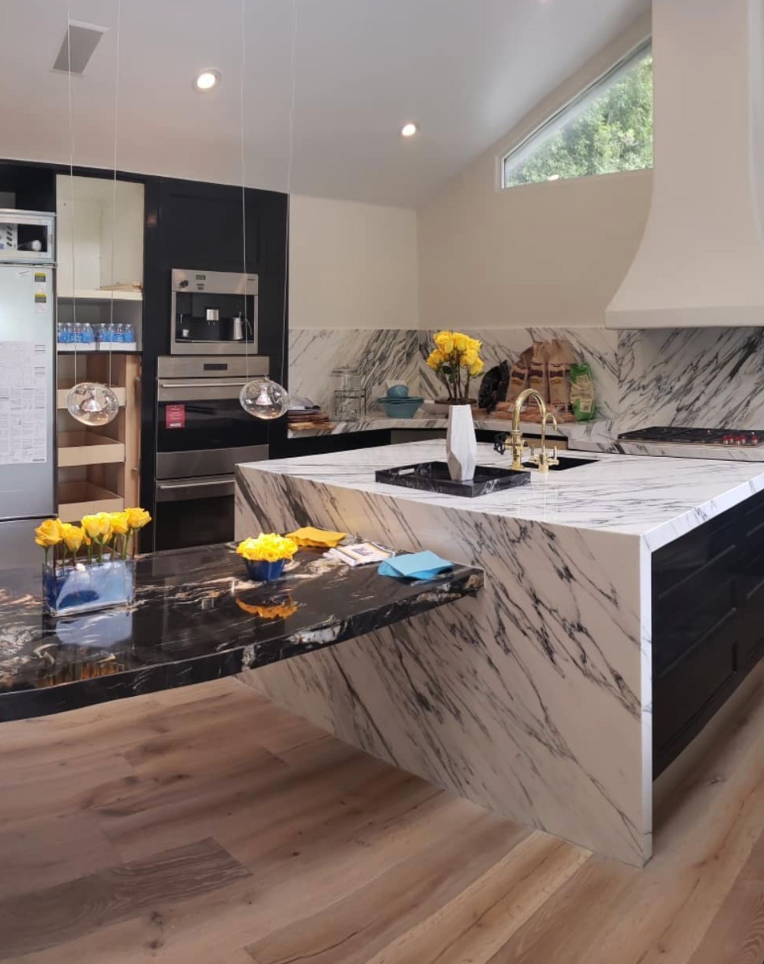 A kitchen with marble counter tops and black cabinets
