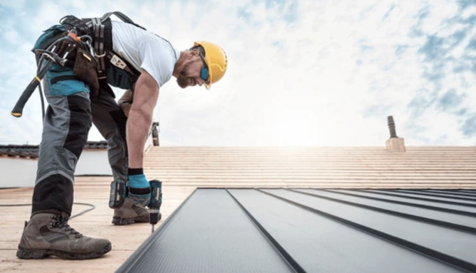 A man is working on a roof with a drill.