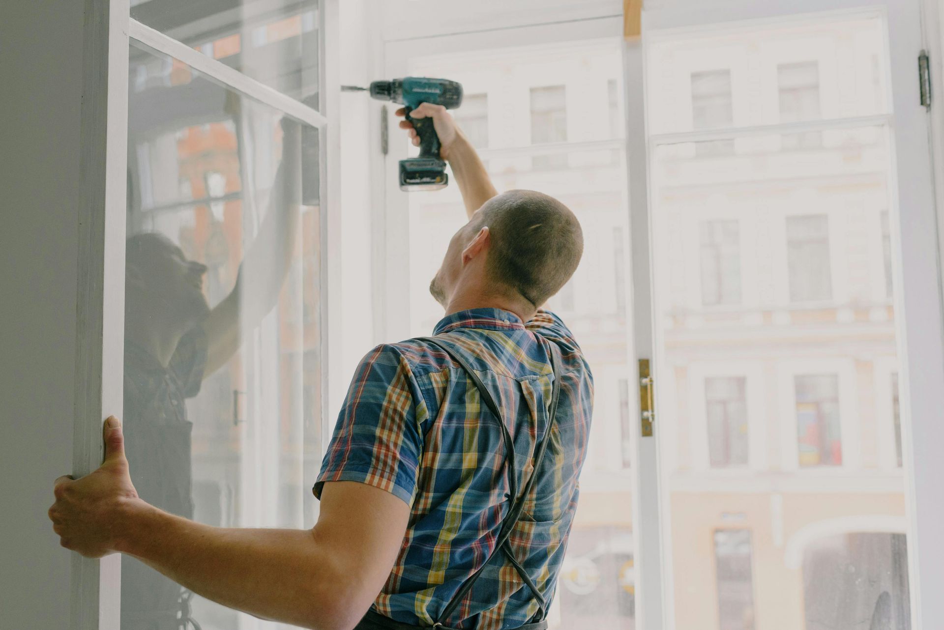 A man is using a drill to install a window.