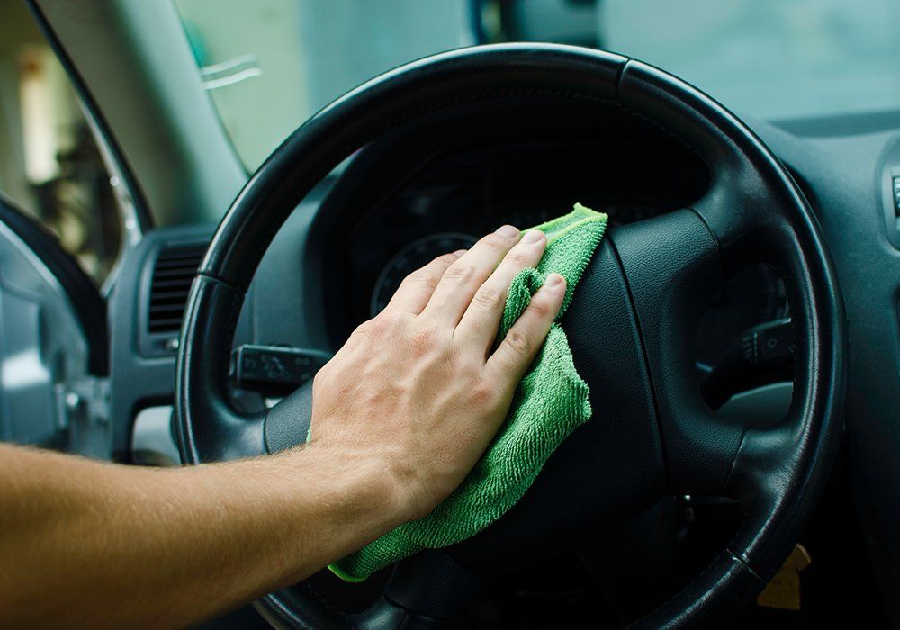 Person Cleaning The Steering Wheel — Hutchinson, MN — Sullivan Mobile Detailing Person Cleaning The Steering Wheel — Hutchinson, MN — Sullivan Mobile Detailing