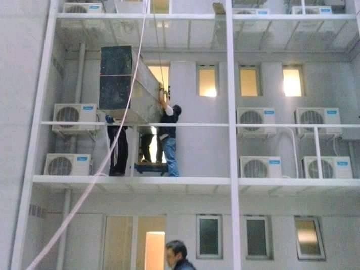 Dos personas en la fachada de un edificio inspeccionando o reparando el exterior.