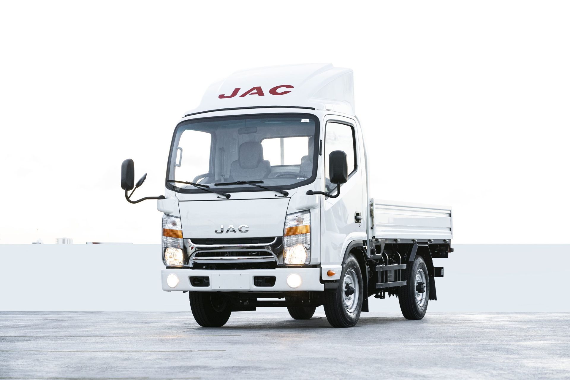 A white jac truck is parked in a parking lot.