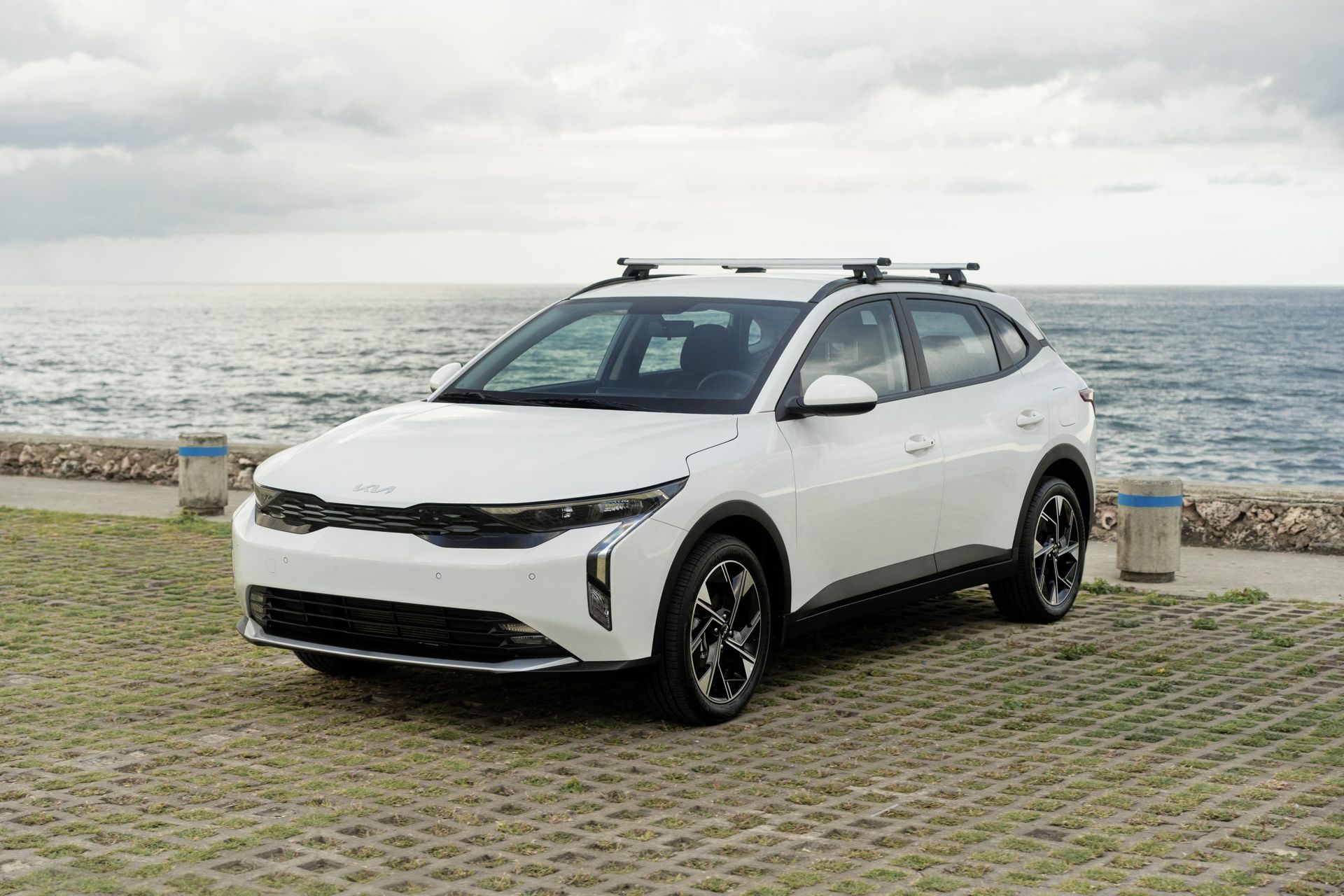 A white car is parked in front of the ocean.