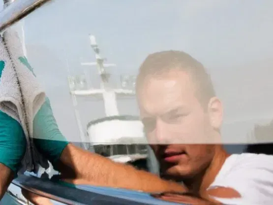 reflection  of a guy waxing a boat in 