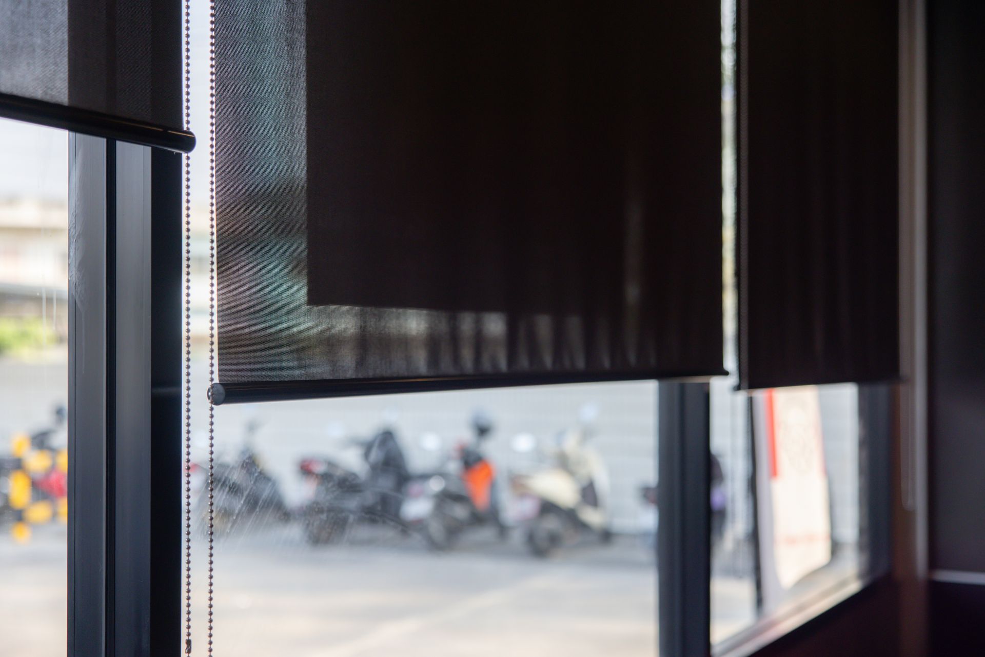 Black roller shades covering large windows inside a modern commercial space.